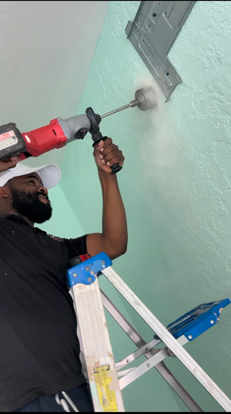 A technician core-drilling a wall for a line set