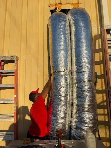 A technician hanging flex duct
